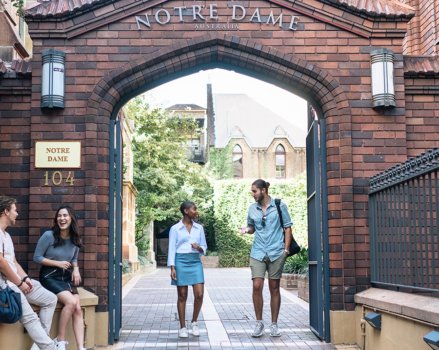 A girl and boy walking through the gate of Notre Dame University, Sydney